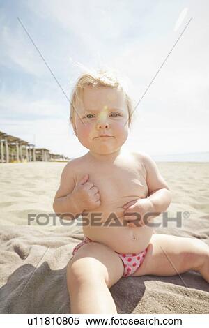 Frowning baby sitting on towel on beach View Large Photo Image Stock Photography - Frowning baby sitting on towel on beach. Fotosearch