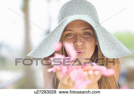 Stock Photo - Girl in sunhat playing with flowers. Fotosearch