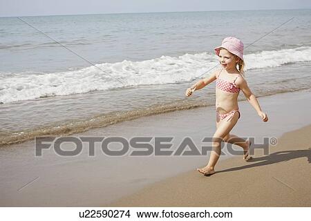 Picture - Girl in sunhat running on beach. Fotosearch