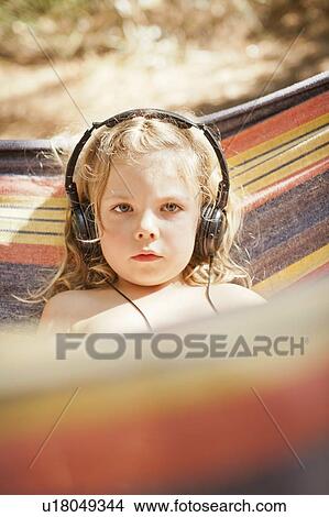 Picture - Girl listening to headphones outdoors. Fotosearch