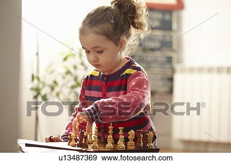Stock Photo - Girl playing chess indoors. Fotosearch