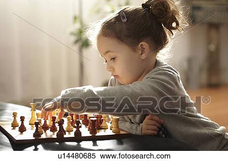 Stock Photography - Girl playing chess indoors. Fotosearch