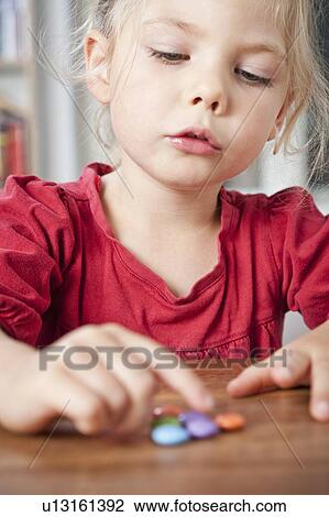 Girl playing with candies on table View Large Photo Image Stock Image - Girl playing with candies on table. Fotosearch