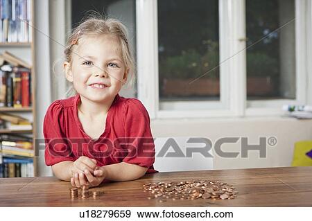 Stock Photo - Girl playing with pennies at table. Fotosearch