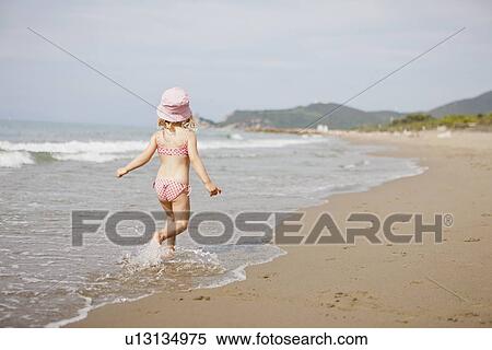 Girl walking in waves on beach View Large Photo Image Stock Photography - Girl walking in waves on beach. Fotosearch