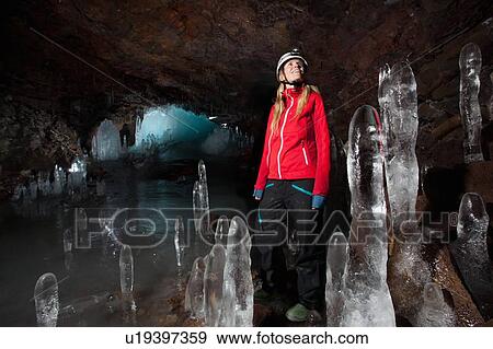 Stock Photo - Hiker with stalactites in glacial cave. Fotosearch