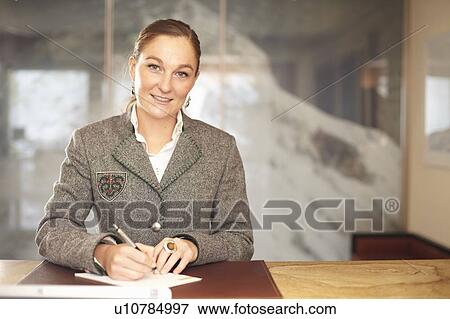 Stock Photo - Hotel concierge writing at desk. Fotosearch