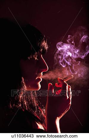 Stock Image - Illuminated profile of woman smoking. Fotosearch