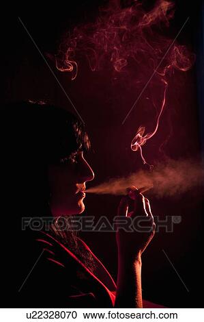 Stock Image - Illuminated profile of woman smoking. Fotosearch