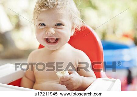 Laughing toddler eating in high chair View Large Photo Image Stock Photography - Laughing toddler eating in high chair. Fotosearch