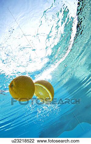 Stock Image - Lemon floating in swimming pool. Fotosearch