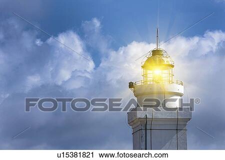 Stock Image - Lighthouse shining against blue sky. Fotosearch