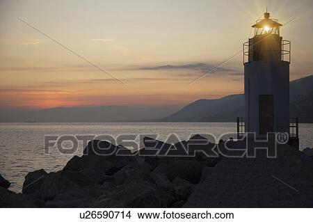 Lighthouse shining over rocky beach View Large Photo Image Picture - Lighthouse shining over rocky beach. Fotosearch