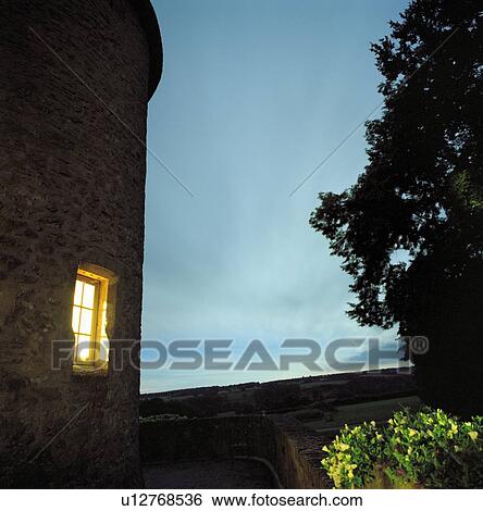 Stock Photograph - Lit window of stone house. Fotosearch