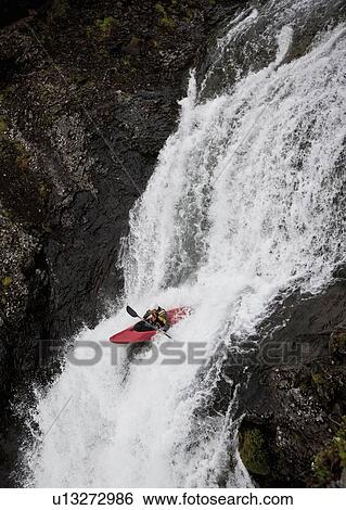 Stock Photograph - Man canoeing over rocky waterfall. Fotosearch