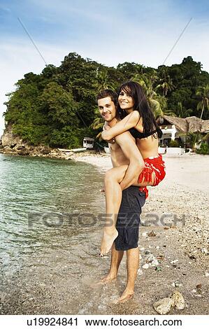 Man carrying girlfriend on beach View Large Photo Image Stock Image - Man carrying girlfriend on beach. Fotosearch