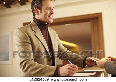 Stock Photo - Man checking in to hotel. Fotosearch