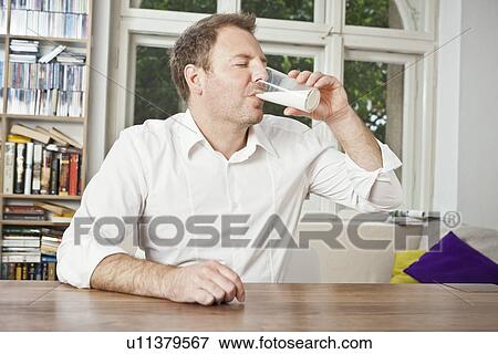 Man drinking glass of milk at table View Large Photo Image Stock Photo - Man drinking glass of milk at table. Fotosearch