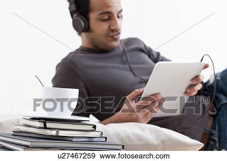 Stock Photo - Man listening to tablet computer. Fotosearch