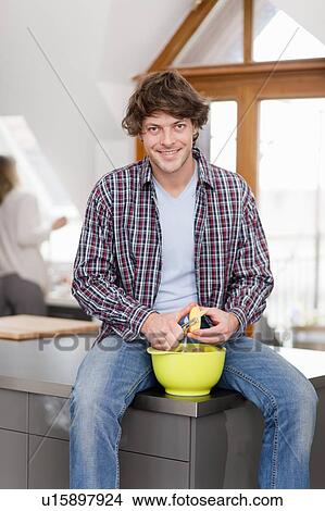 Picture - Man peeling vegetables in kitchen. Fotosearch