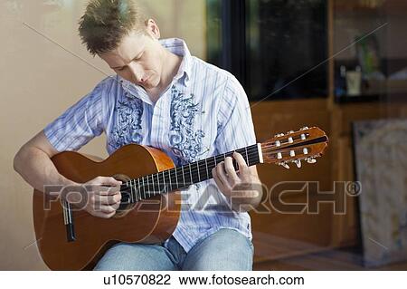 Man playing guitar in living room View Large Photo Image Stock Image - Man playing guitar in living room. Fotosearch