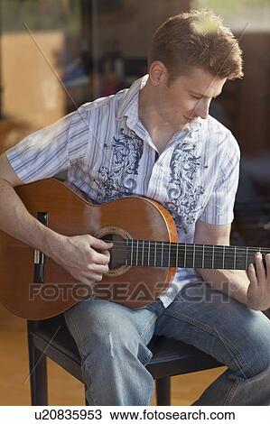 Man playing guitar in living room View Large Photo Image Stock Image - Man playing guitar in living room. Fotosearch