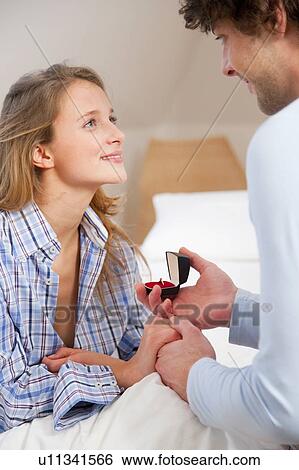 Stock Photograph - Man proposing to girlfriend on bed. Fotosearch