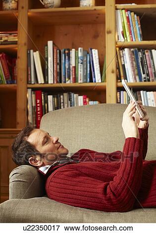 Man reading book on sofa View Large Photo Image Stock Photo - Man reading book on sofa. Fotosearch
