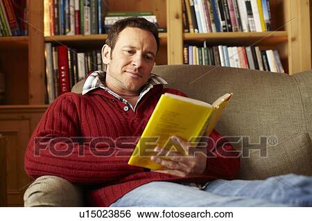 Man reading book on sofa View Large Photo Image Stock Photograph - Man reading book on sofa. Fotosearch