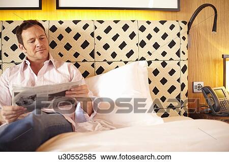 Man reading newspaper on bed View Large Photo Image Stock Photography - Man reading newspaper on bed. Fotosearch