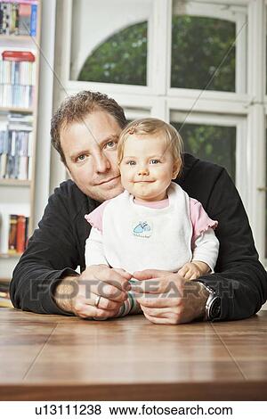 Man sitting with baby on table View Large Photo Image Stock Photo - Man sitting with baby on table. Fotosearch