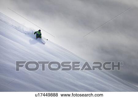 Stock Photo - Man skiing on snowy hillside. Fotosearch