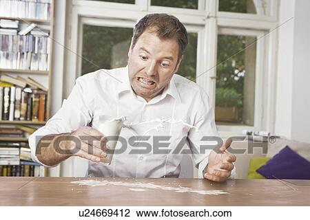 Stock Image - Man spilling milk on table. Fotosearch