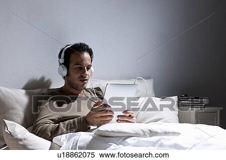 Man using tablet computer in bed View Large Photo Image Stock Photography - Man using tablet computer in bed. Fotosearch