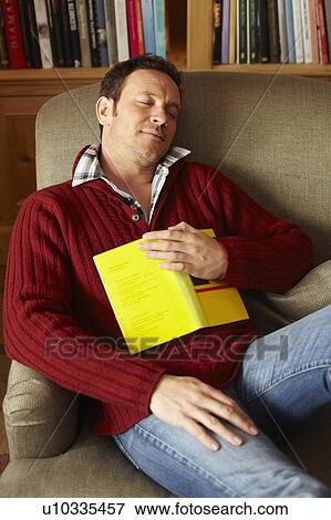 Stock Photo - Man with book sleeping on sofa. Fotosearch