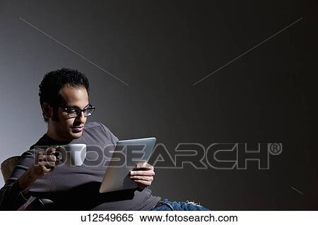 Stock Photography - Man with coffee using tablet computer. Fotosearch