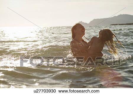 Mother and daughter playing in ocean View Large Photo Image Stock Image - Mother and daughter playing in ocean. Fotosearch