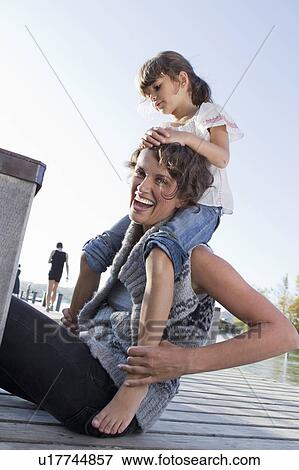 Stock Photo - Mother and daughter sitting on pier. Fotosearch