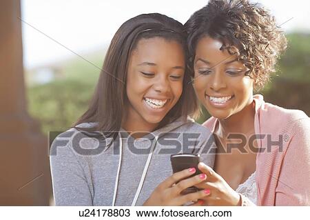 Stock Image - Mother and daughter using cell phone. Fotosearch
