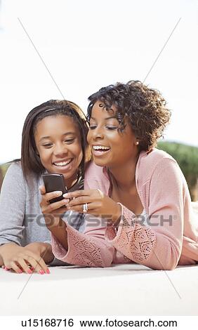 Stock Photograph - Mother and daughter using cell phone. Fotosearch