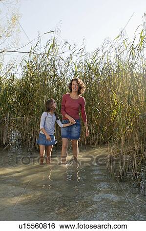 Stock Photograph - Mother and daughter walking in pond. Fotosearch