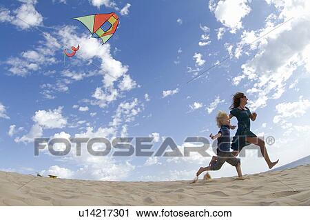 Mother and son flying kite on beach View Large Photo Image Stock Image - Mother and son flying kite on beach. Fotosearch