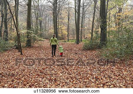 Stock Photograph - Mother and son walking in autumn leaves. Fotosearch