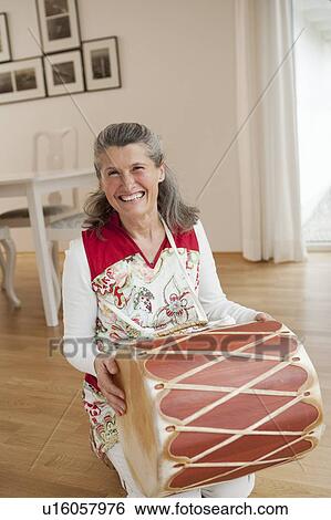 Older woman holding drum View Large Photo Image Stock Photograph - Older woman holding drum. Fotosearch