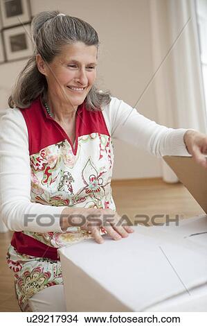 Older woman unpacking box View Large Photo Image Picture - Older woman unpacking box. Fotosearch