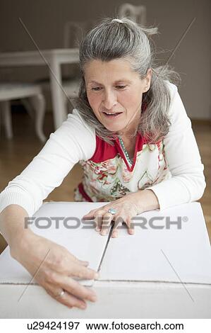 Stock Photo - Older woman wrapping cardboard box. Fotosearch