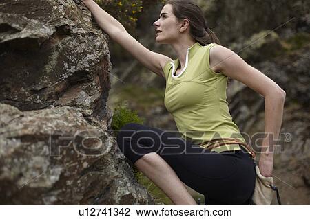 Stock Image - Rock climber scaling boulder. Fotosearch