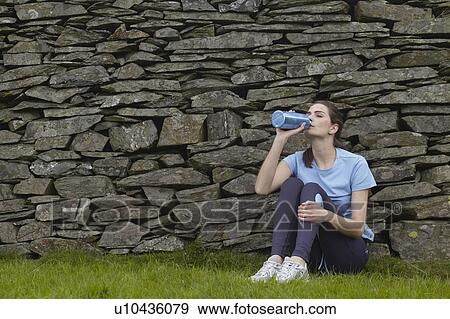 Stock Photo - Runner drinking water against rock wall. Fotosearch