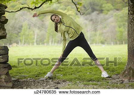 Stock Photography - Runner stretching in rural field. Fotosearch