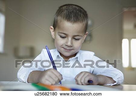 Stock Image - Schoolboy writing at desk. Fotosearch